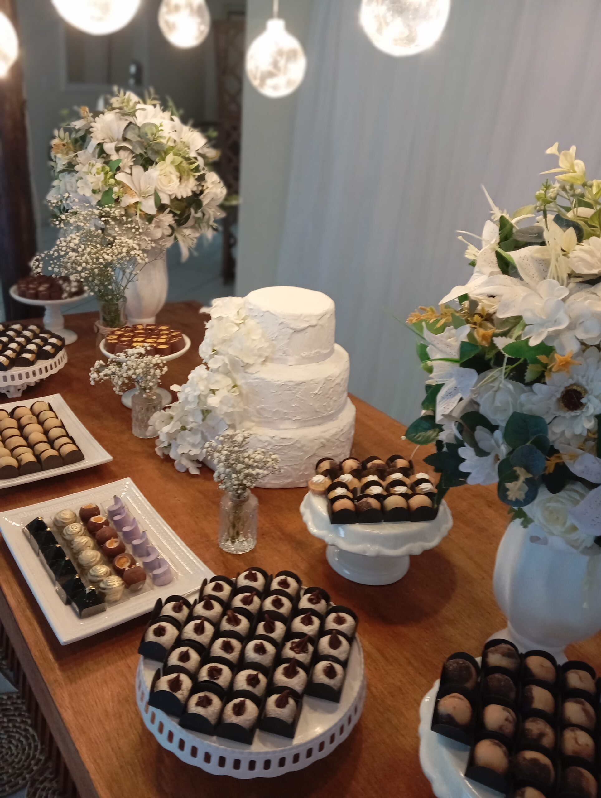 Mesa de doces de casamento decorada com bolo branco e arranjos florais